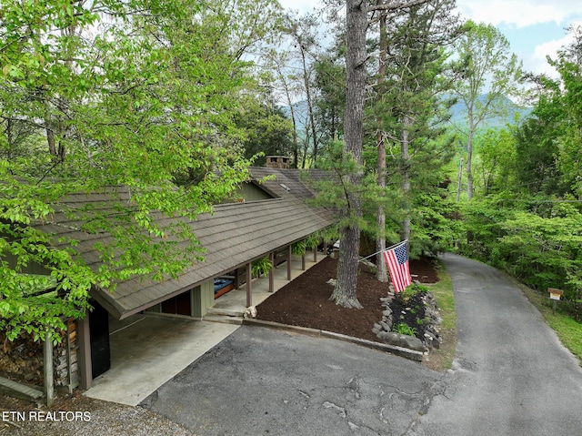 exterior space featuring driveway and a shingled roof