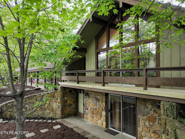 back of house featuring a balcony and stone siding