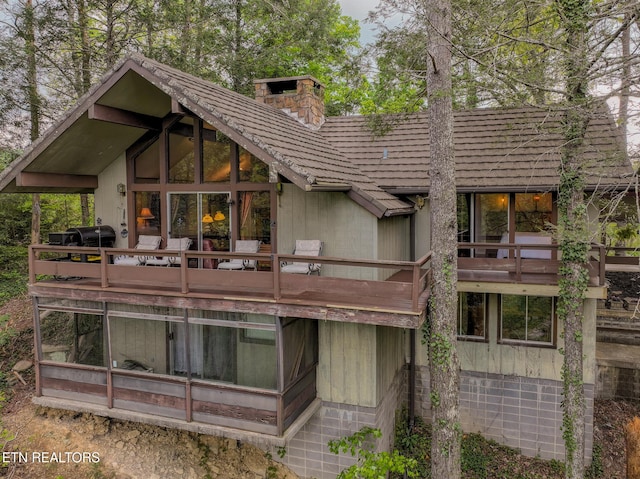back of property with a chimney and a balcony