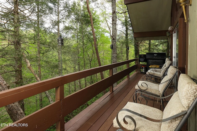 wooden terrace featuring area for grilling and a forest view