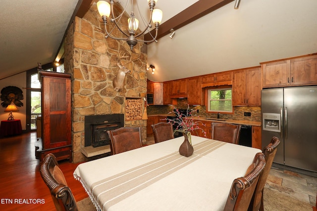 dining area with an inviting chandelier, high vaulted ceiling, a fireplace, and beam ceiling
