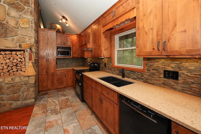 kitchen featuring tasteful backsplash, light stone counters, a sink, black appliances, and vaulted ceiling