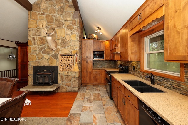 kitchen featuring brown cabinetry, tasteful backsplash, a sink, black appliances, and vaulted ceiling