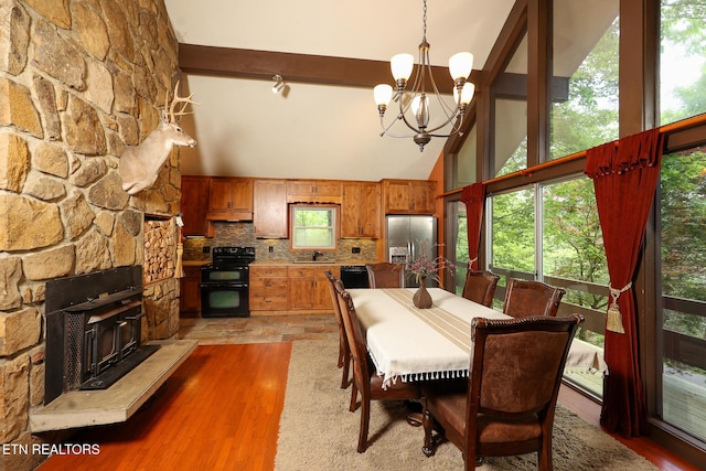 dining area featuring an inviting chandelier, beamed ceiling, light wood-style flooring, and a wealth of natural light