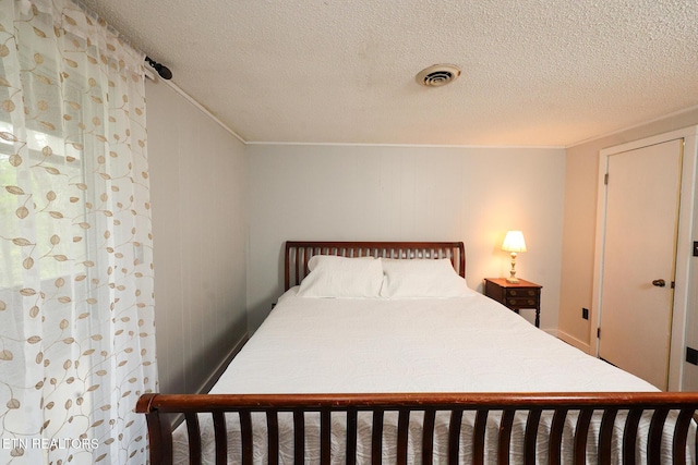 bedroom featuring ornamental molding, a textured ceiling, and visible vents