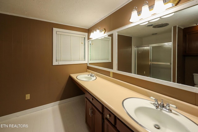 bathroom with double vanity, a sink, baseboards, and a stall shower