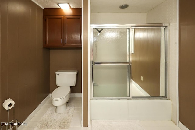 full bathroom with tile patterned flooring, bath / shower combo with glass door, and toilet