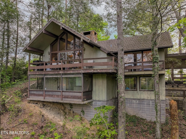 back of property featuring a chimney and a balcony