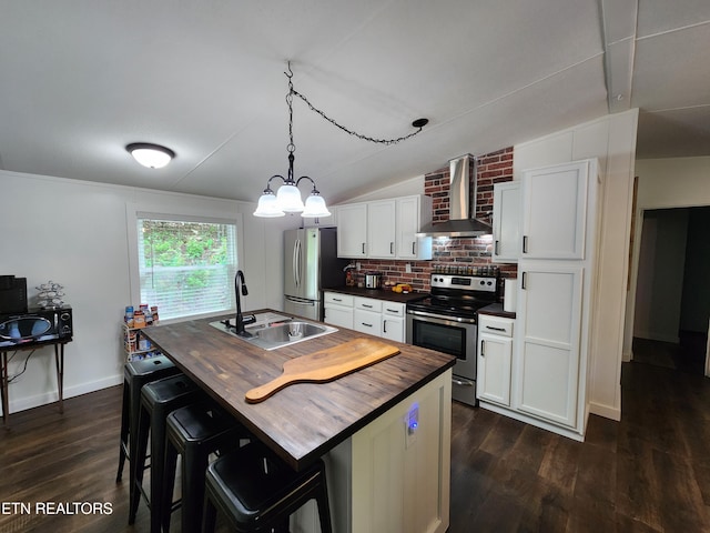 kitchen with butcher block counters, wall chimney exhaust hood, a sink, dark wood finished floors, and appliances with stainless steel finishes