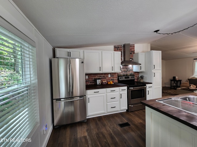 kitchen with lofted ceiling, wooden counters, wall chimney exhaust hood, dark wood finished floors, and appliances with stainless steel finishes