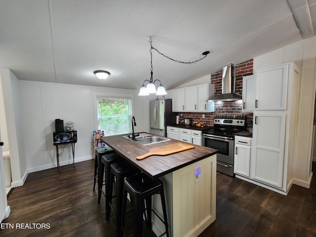 kitchen featuring wooden counters, wall chimney range hood, dark wood-type flooring, a sink, and stainless steel appliances