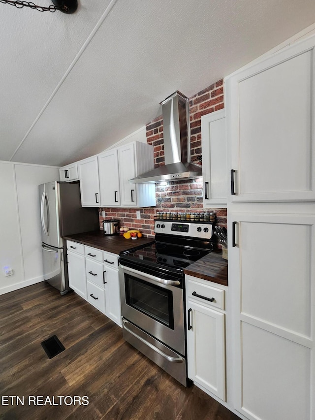 kitchen featuring wall chimney range hood, white cabinets, appliances with stainless steel finishes, wood counters, and dark wood finished floors