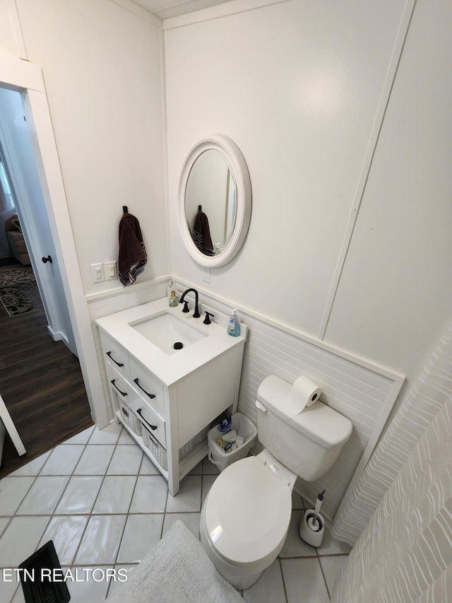 bathroom featuring toilet, wainscoting, tile patterned flooring, and vanity