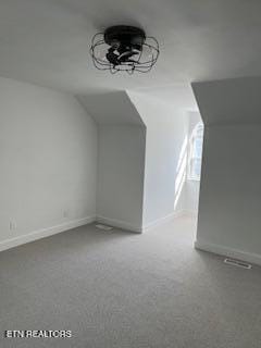 additional living space with vaulted ceiling, baseboards, and visible vents
