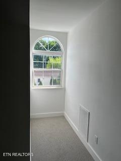empty room with carpet flooring, visible vents, and baseboards