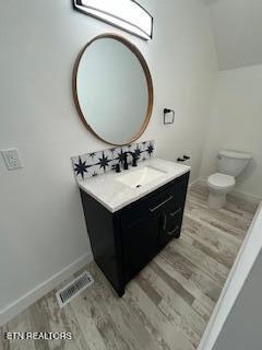 bathroom with vanity, toilet, visible vents, and wood finished floors