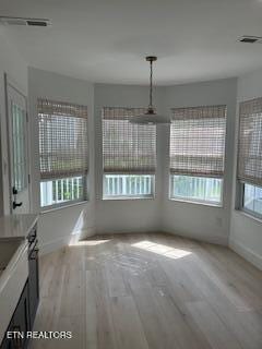 unfurnished dining area with light wood-style flooring, baseboards, and visible vents