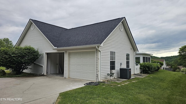 view of property exterior featuring roof with shingles, central AC, driveway, a yard, and a garage