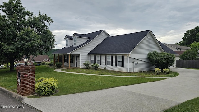 view of front of property featuring concrete driveway, a shingled roof, a front lawn, and fence