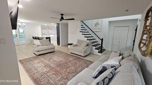 living area with recessed lighting, visible vents, ceiling fan with notable chandelier, stairs, and wood finished floors