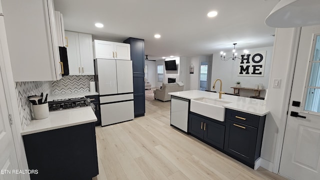 kitchen featuring freestanding refrigerator, light wood-style flooring, dishwasher, a sink, and light countertops