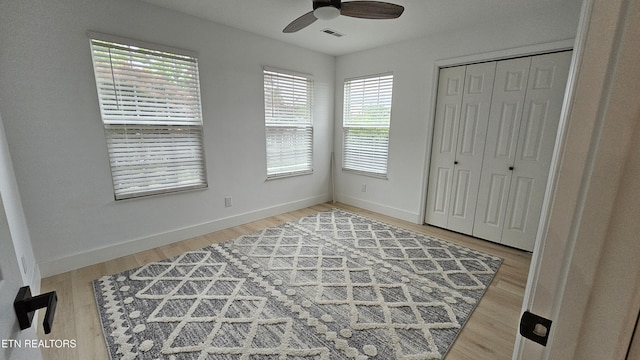 unfurnished bedroom featuring light wood-style flooring, a ceiling fan, a closet, visible vents, and baseboards