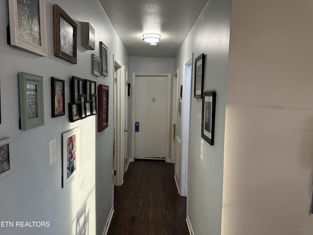 hallway featuring baseboards and dark wood-type flooring