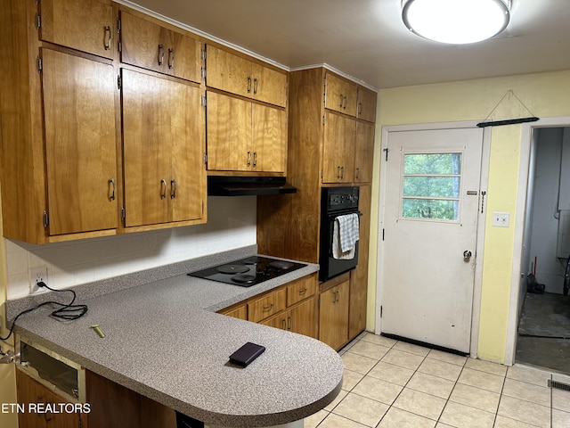 kitchen featuring under cabinet range hood, brown cabinets, light tile patterned floors, and black appliances