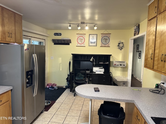 kitchen with brown cabinets, light tile patterned floors, stainless steel fridge with ice dispenser, light countertops, and a peninsula