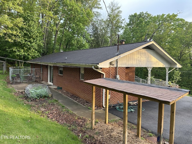 back of property featuring roof with shingles, a gate, fence, and brick siding