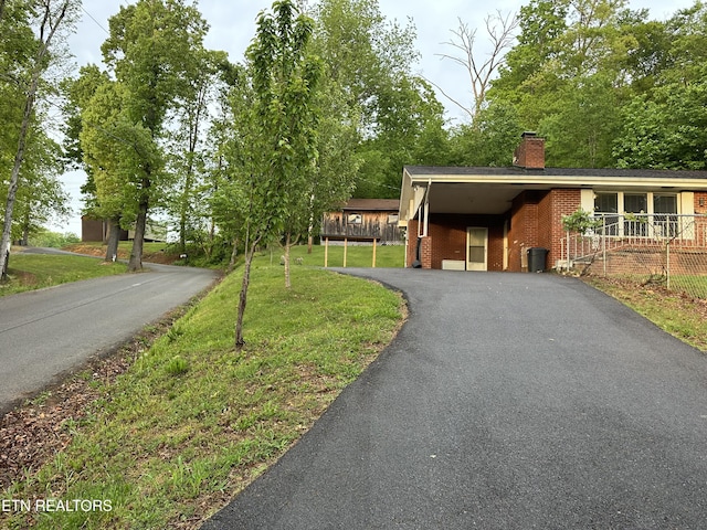 view of front facade with a chimney, driveway, a front lawn, and brick siding