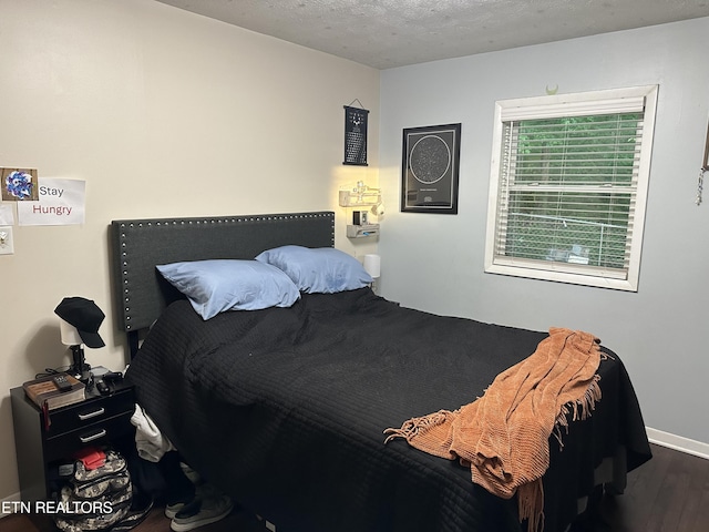 bedroom with baseboards, a textured ceiling, and wood finished floors