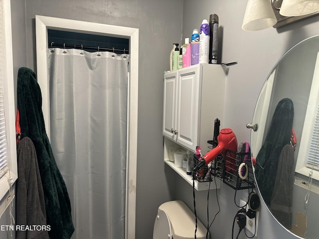 full bath with toilet and a shower with curtain