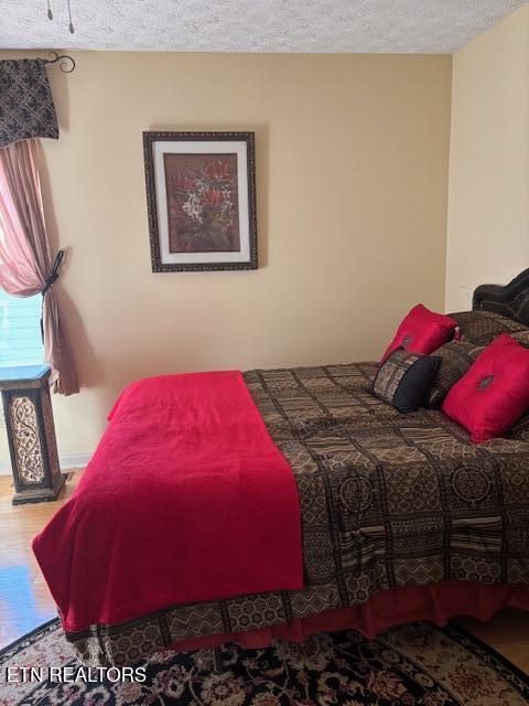 bedroom featuring a textured ceiling and wood finished floors
