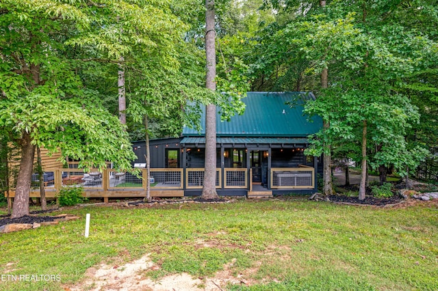 back of house with a yard, a wooden deck, and metal roof
