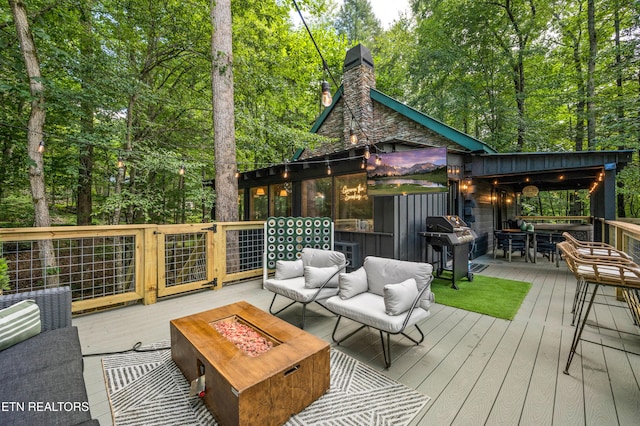 wooden terrace featuring an outdoor living space with a fire pit and a grill