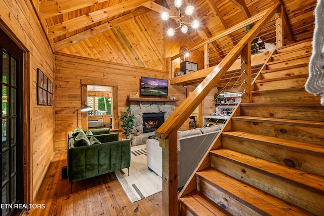 staircase with beamed ceiling, wood walls, wood-type flooring, and wooden ceiling