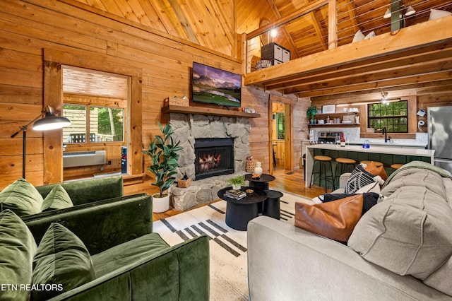 living room featuring wood finished floors, high vaulted ceiling, a fireplace, wood walls, and wooden ceiling