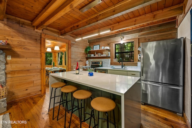 kitchen with wood ceiling, a sink, beam ceiling, stainless steel appliances, and hardwood / wood-style floors