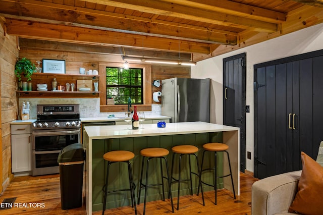 kitchen with a center island, wood finished floors, stainless steel appliances, beamed ceiling, and light countertops