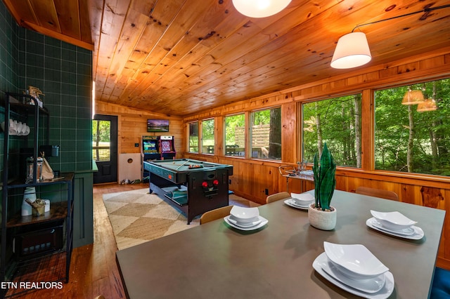 game room with a wealth of natural light, vaulted ceiling, and wooden walls