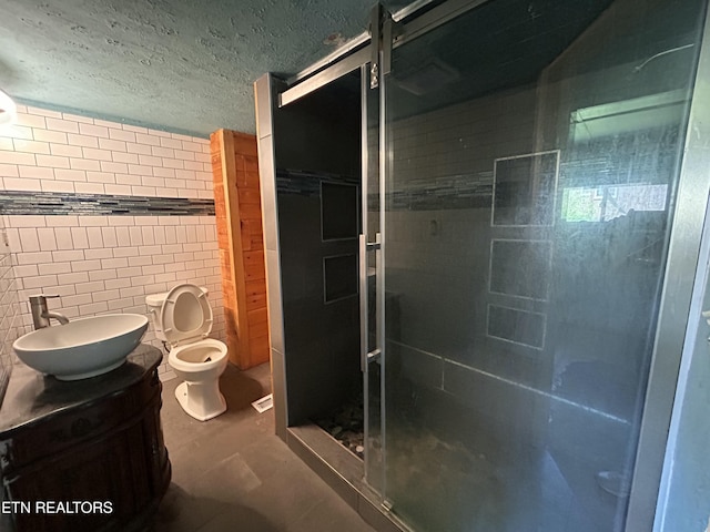 full bathroom with vanity, toilet, tile walls, tile patterned floors, and a shower stall