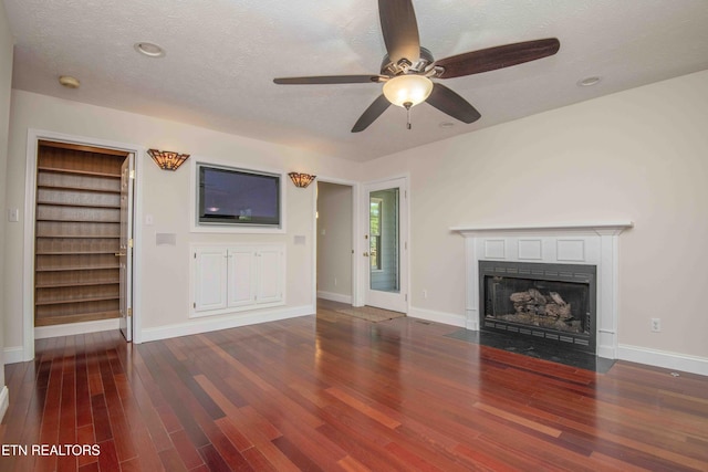 unfurnished living room featuring a fireplace with flush hearth, baseboards, ceiling fan, and wood finished floors