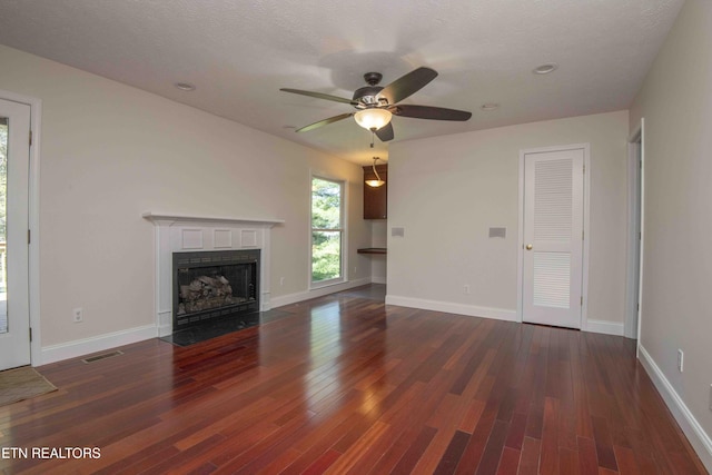 unfurnished living room with visible vents, wood finished floors, baseboards, ceiling fan, and a fireplace with flush hearth