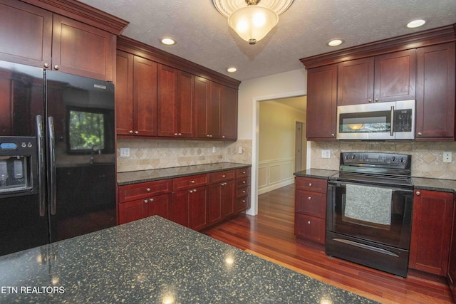 kitchen featuring dark wood-style flooring, dark brown cabinets, dark stone countertops, decorative backsplash, and black appliances
