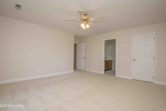 unfurnished bedroom with light colored carpet, connected bathroom, baseboards, and visible vents