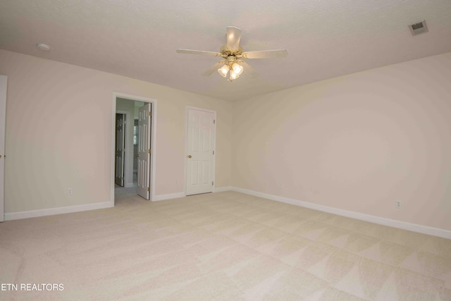 spare room with visible vents, baseboards, ceiling fan, and light colored carpet