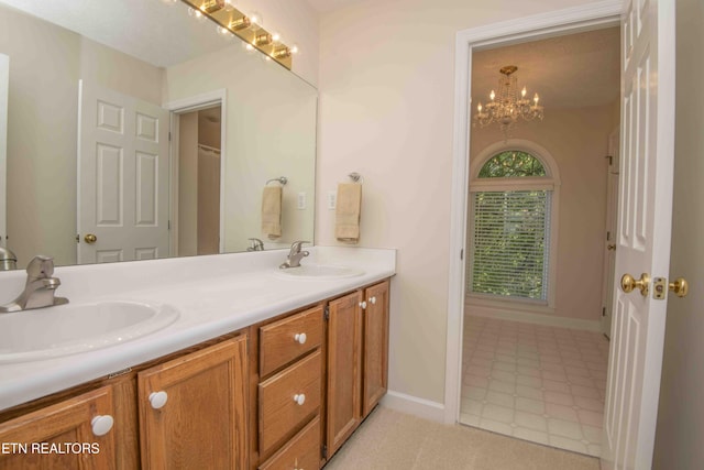 full bath featuring double vanity, a sink, baseboards, and a notable chandelier