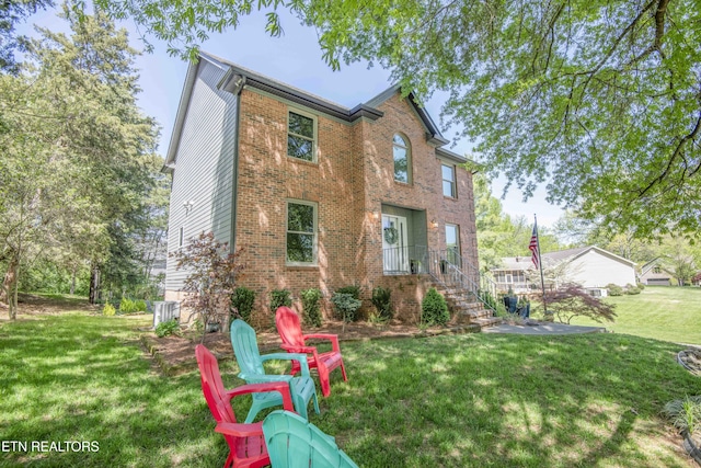 rear view of house featuring a yard, central AC, and brick siding