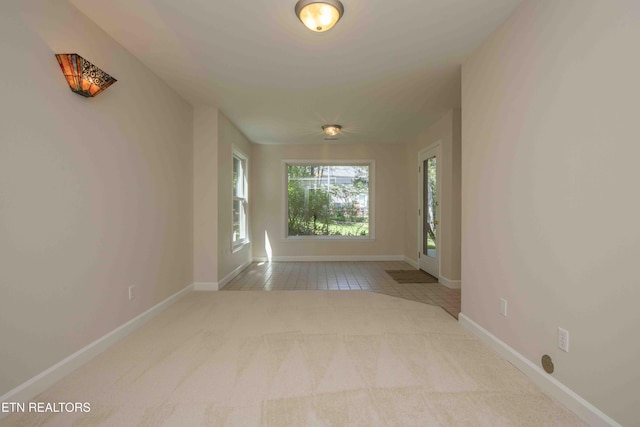 spare room featuring tile patterned floors, baseboards, and carpet floors